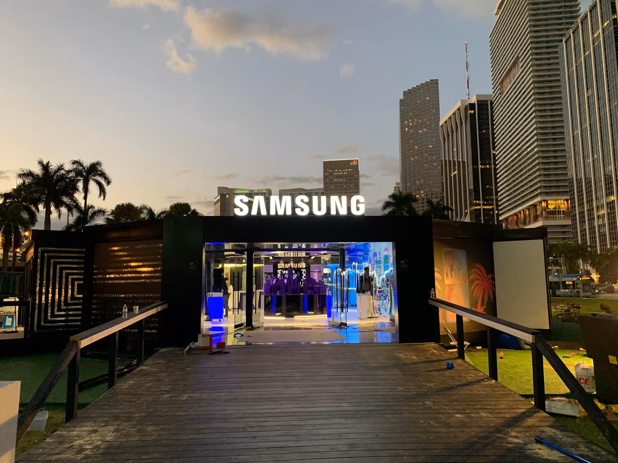 Samsung pop-up store with illuminated sign and modern interior at dusk in an urban setting.