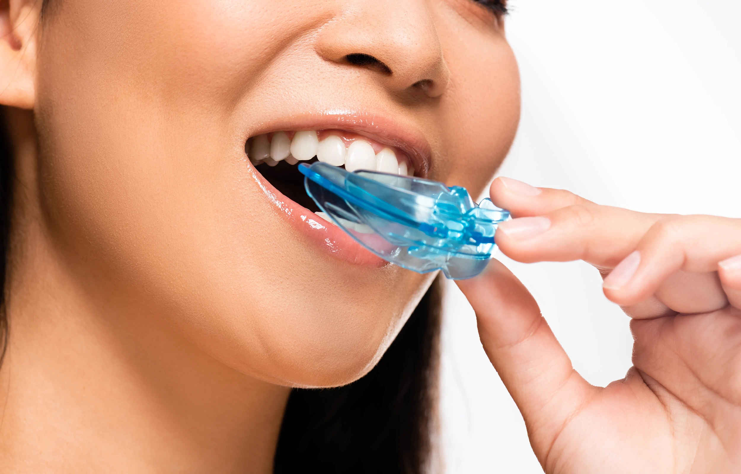 A woman putting her mouth guard in her mouth