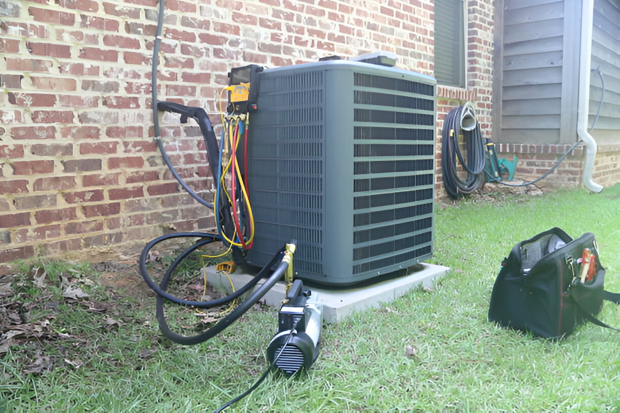 A residential air conditioning unit set up outside, with tools nearby for maintenance.
