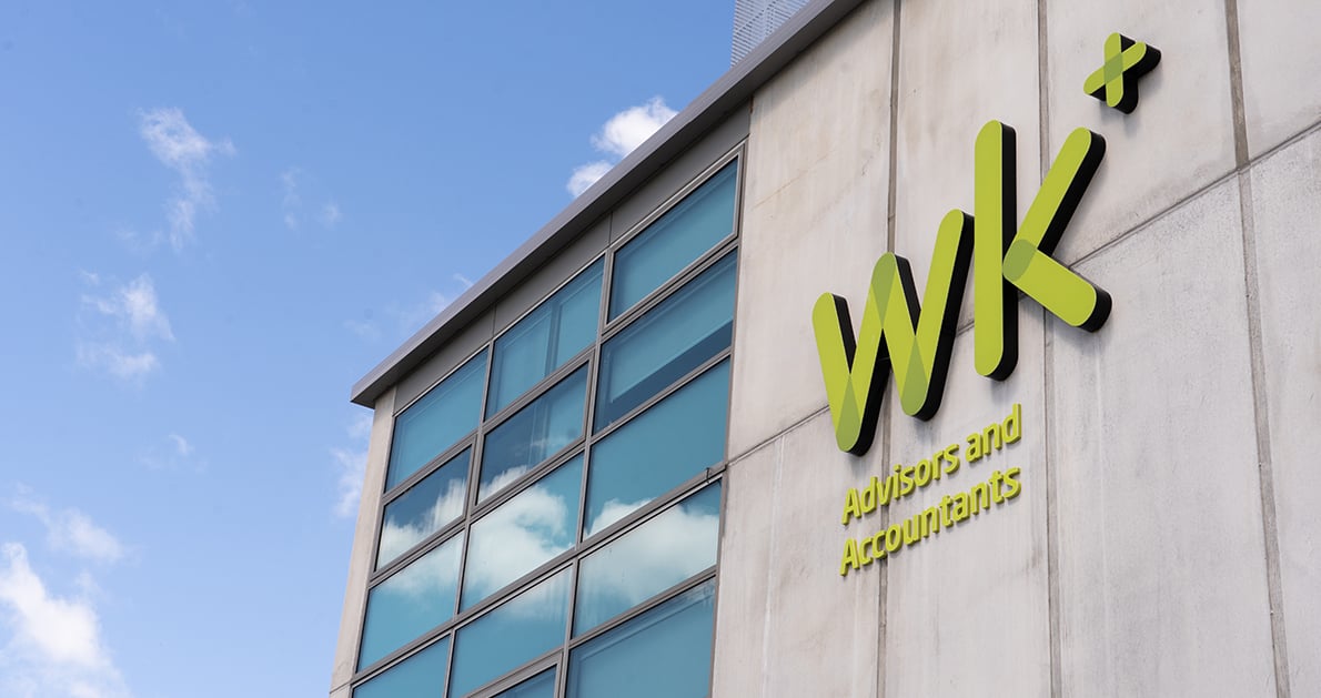 Modern office building with large windows and green WK Advisors and Accountants sign on concrete wall.