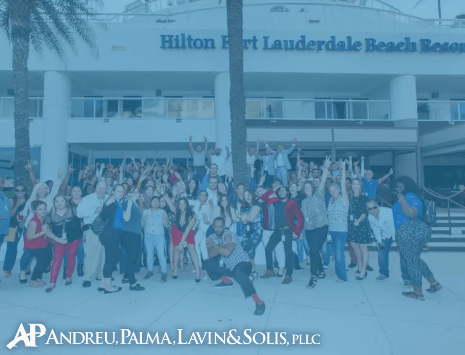 Large group of diverse people posing and celebrating together outside the Hilton Fort Lauderdale Beach Resort.