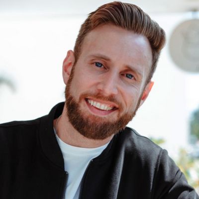 A portrait of Bryce North smiling in casual attire against a neutral background.