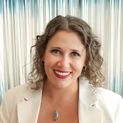 A professional headshot of Holly Callis smiling in front of a softly lit background.