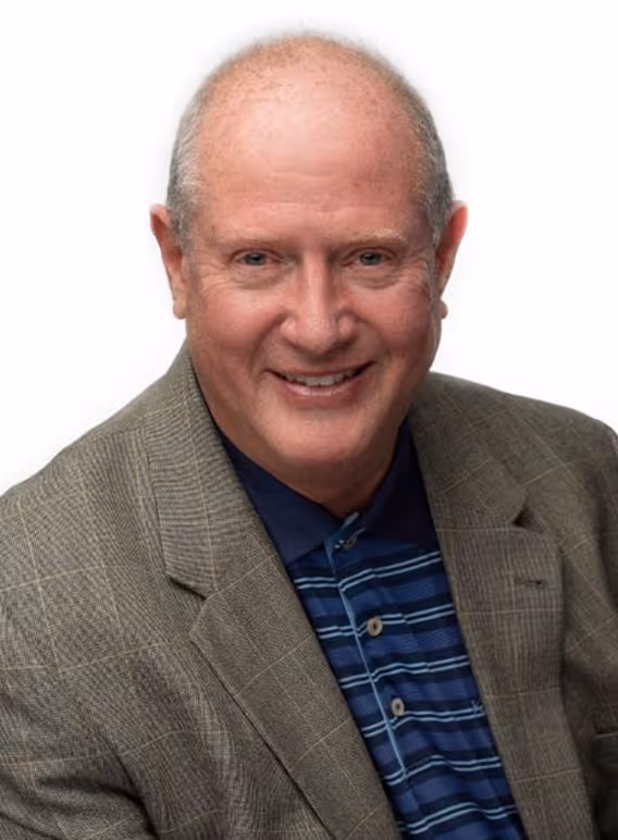 Smiling middle-aged bald man wearing a gray checked blazer and a striped blue polo shirt.