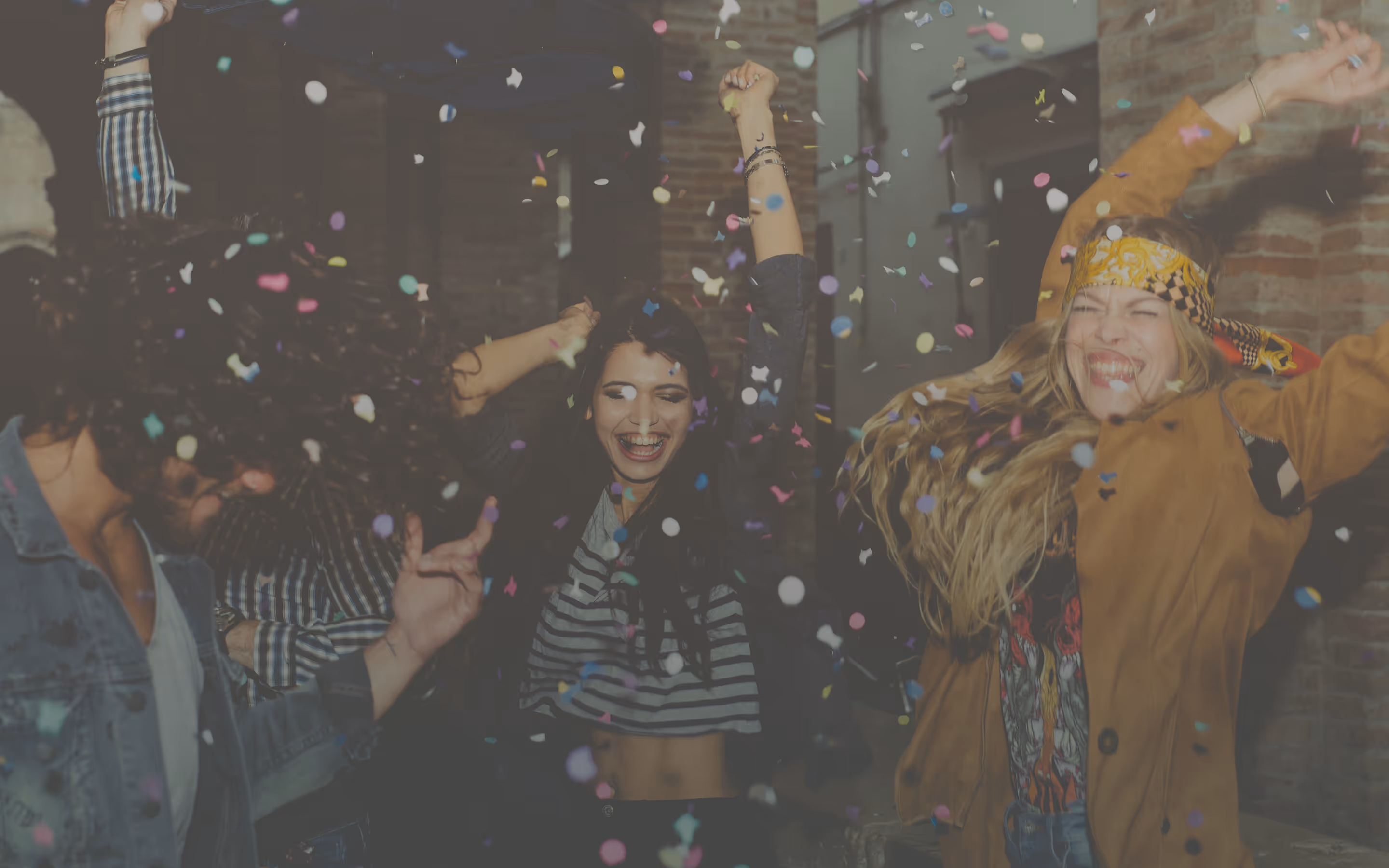 Young people dancing and celebrating with colorful confetti indoors.
