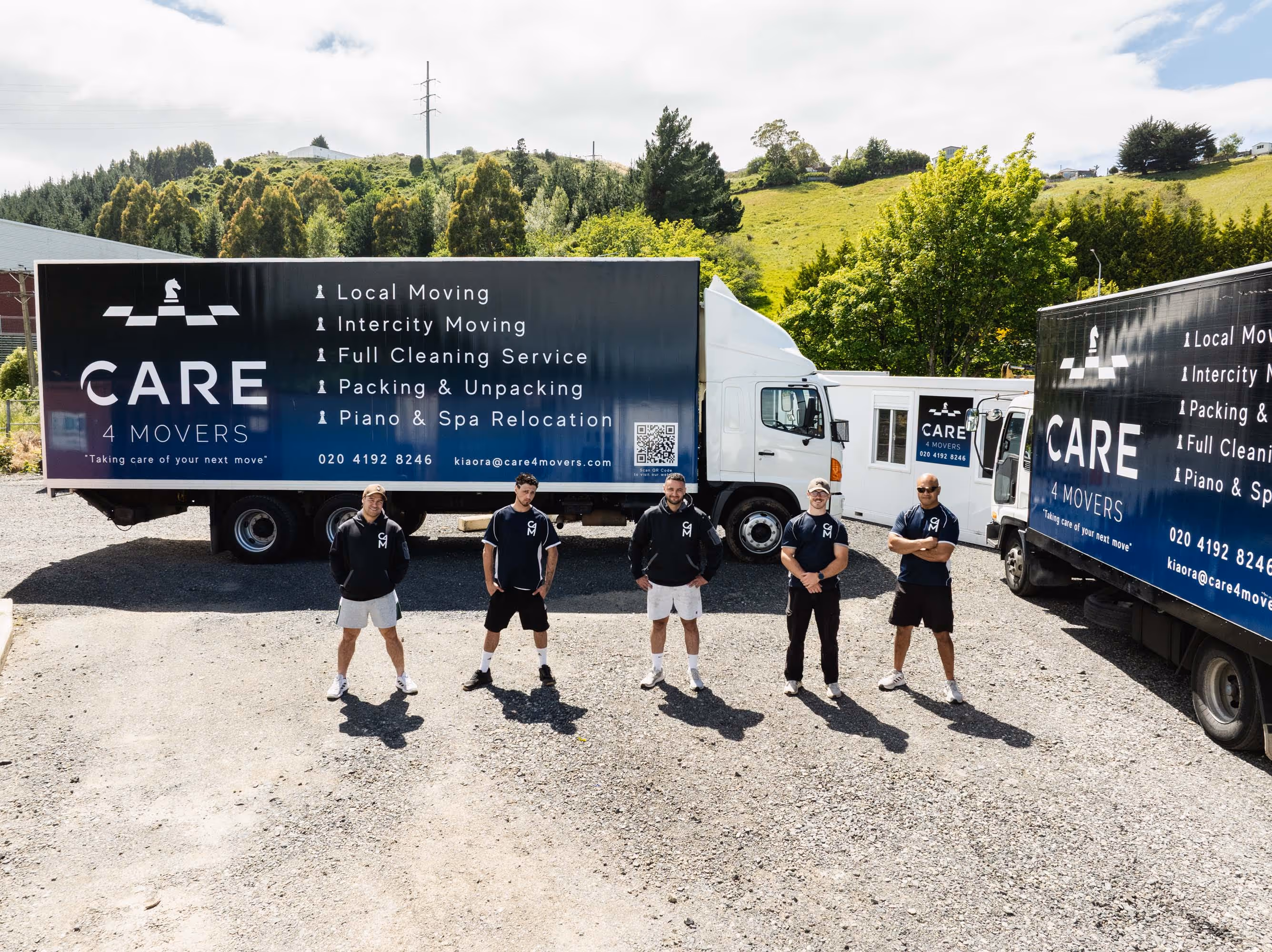 Five men standing in front of two delivery trucks with 'CARE 4 MOVERS' branding and service listings.