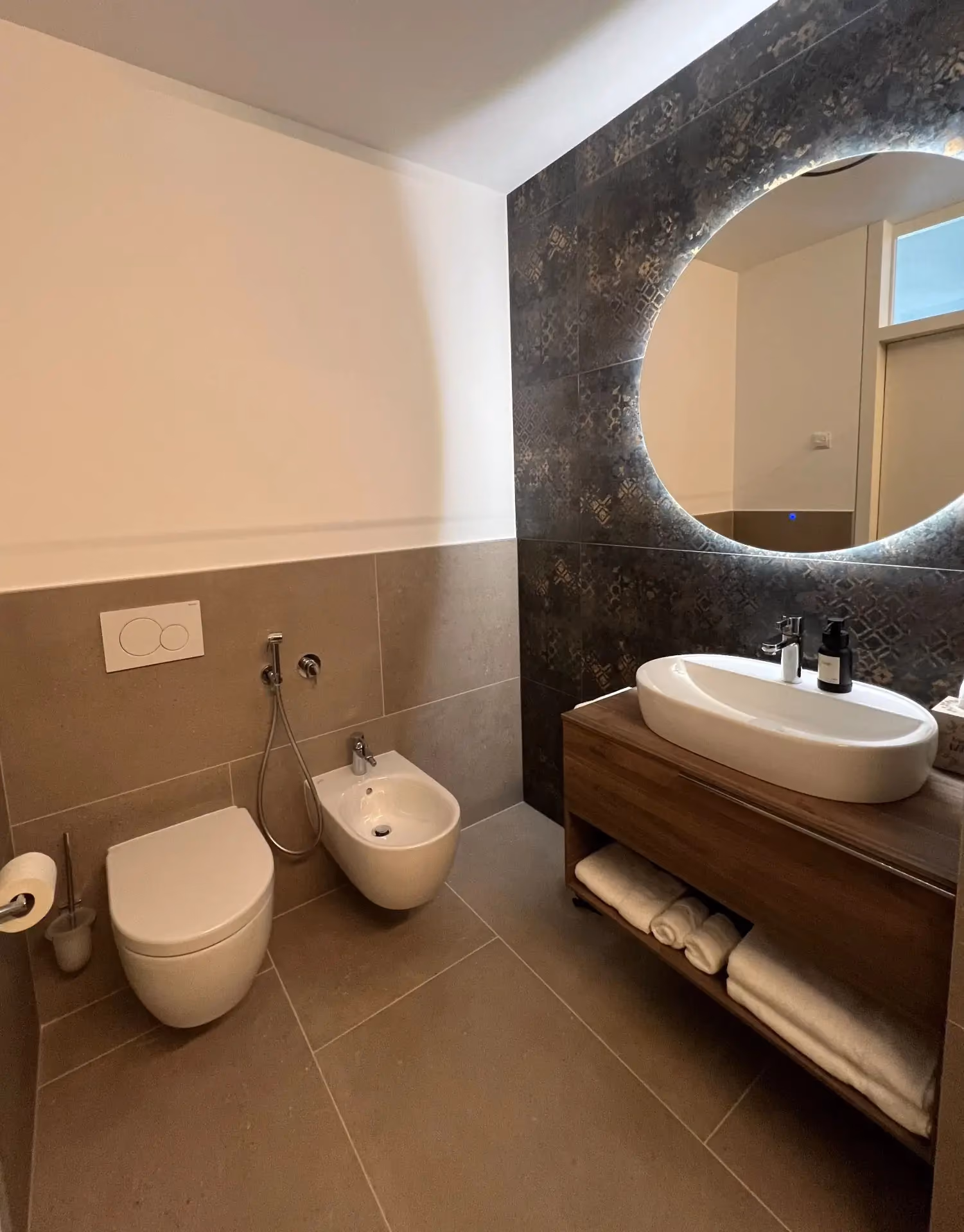 Badezimmer mit Rundspiegel, WC und Bidet