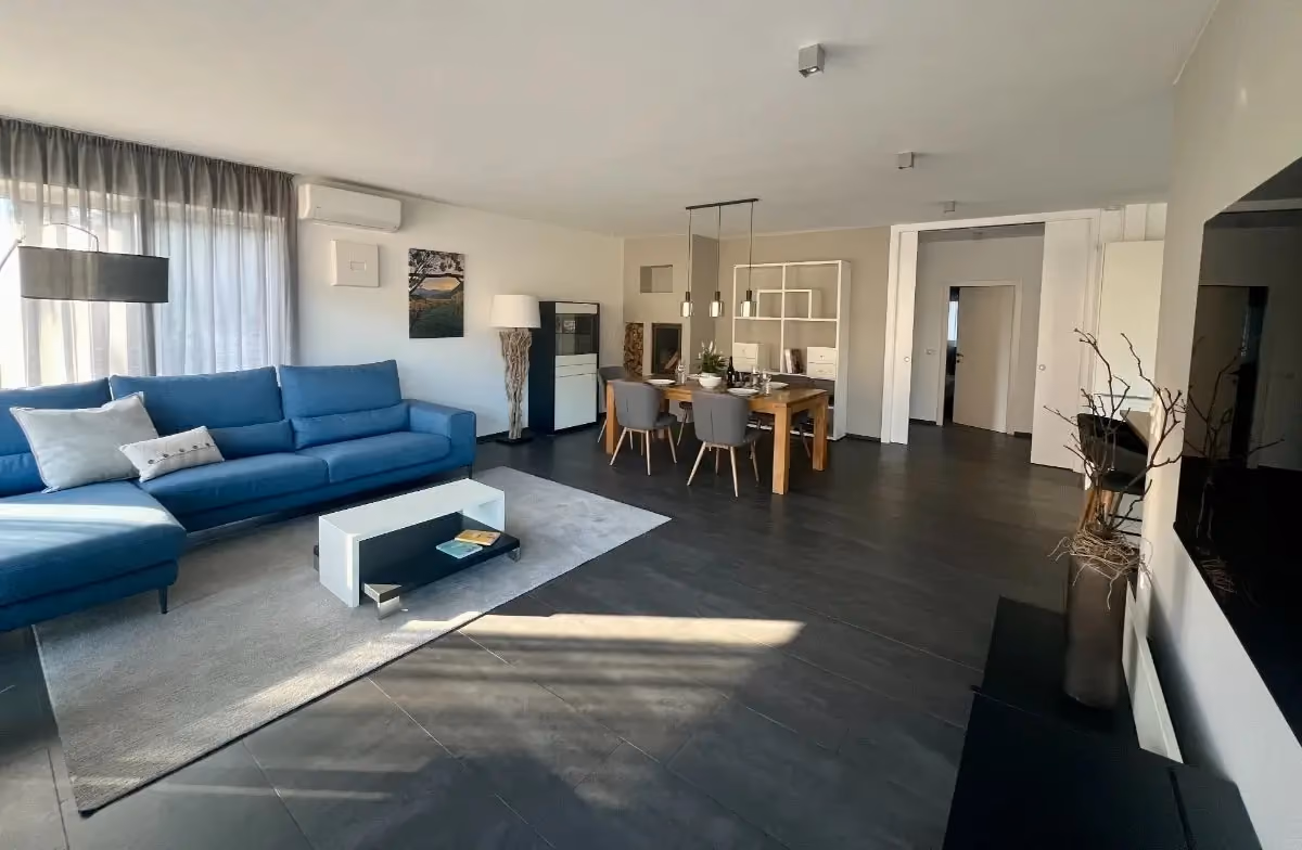 Wohnbereich mit blauem Sofa und Essplatz in der Ferienwohnung