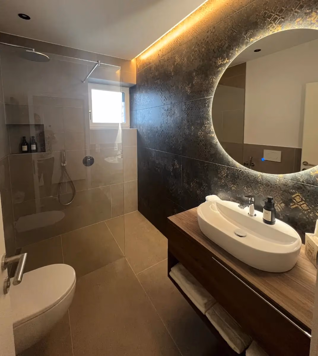 Badezimmer mit beleuchtetem Rundspiegel und Waschtisch