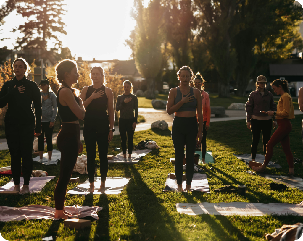 Black and white photograph of people in a yoga pose outdoors.