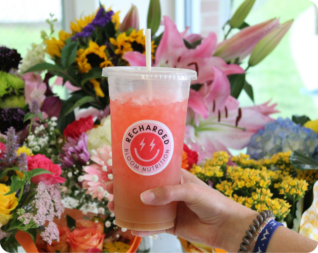 Beverage cup with straw and branding, held by hand.