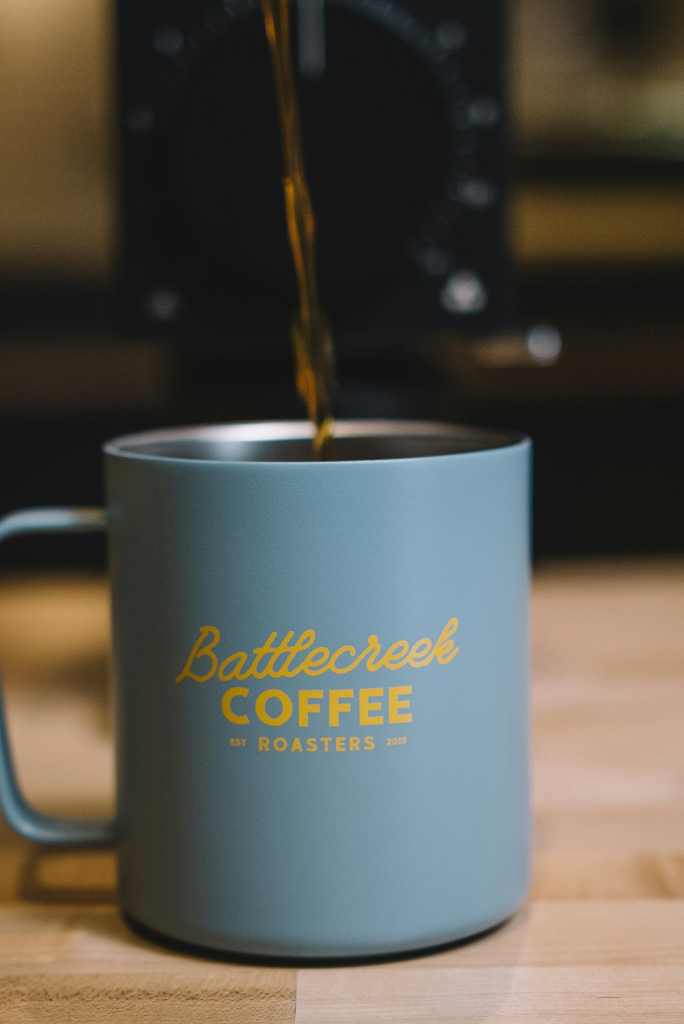 Beverage cup with straw and branding, held by hand.