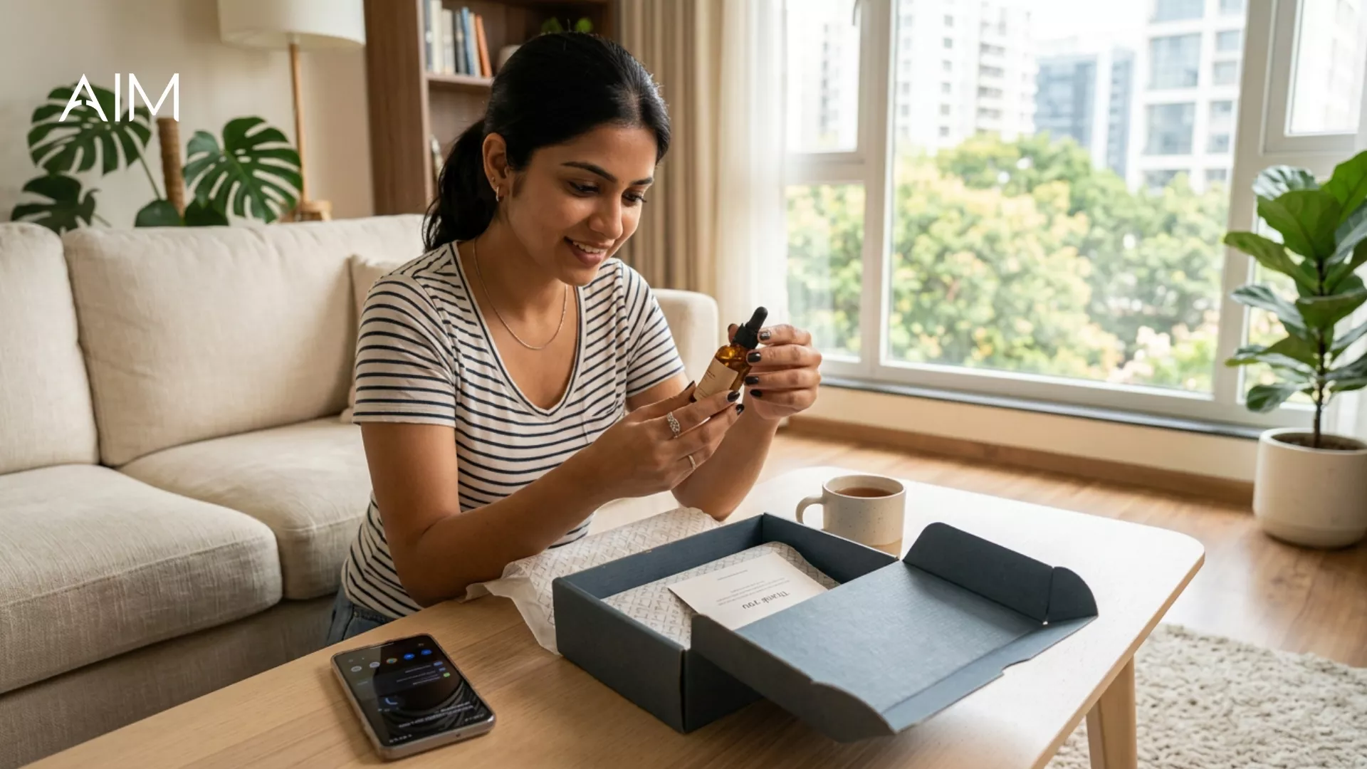 Woman at home holding a small dropper bottle from an open grey box with a thank-you card on her coffee table