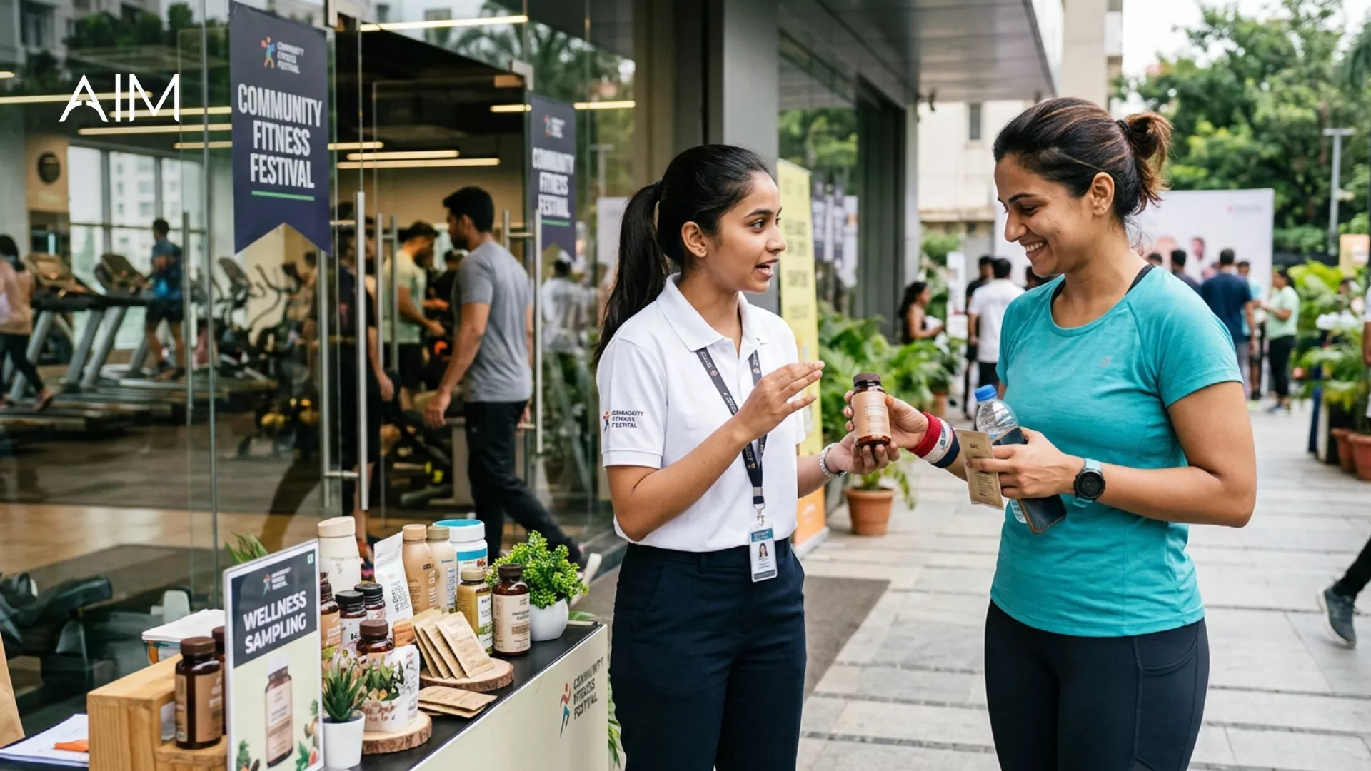 Promoter at a Community Fitness Festival stall talking with a woman in sportswear who holds a sample bottle