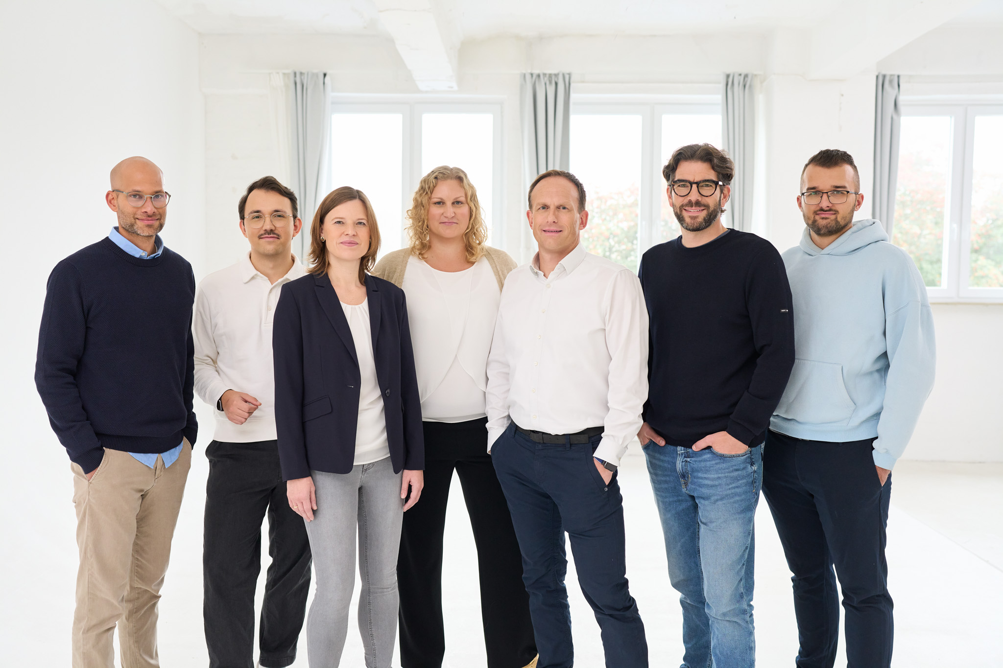 Sieben Mitarbeiter von loyos bi stehen für ein Teamfoto nebeneinander und schauen in die Kamera.