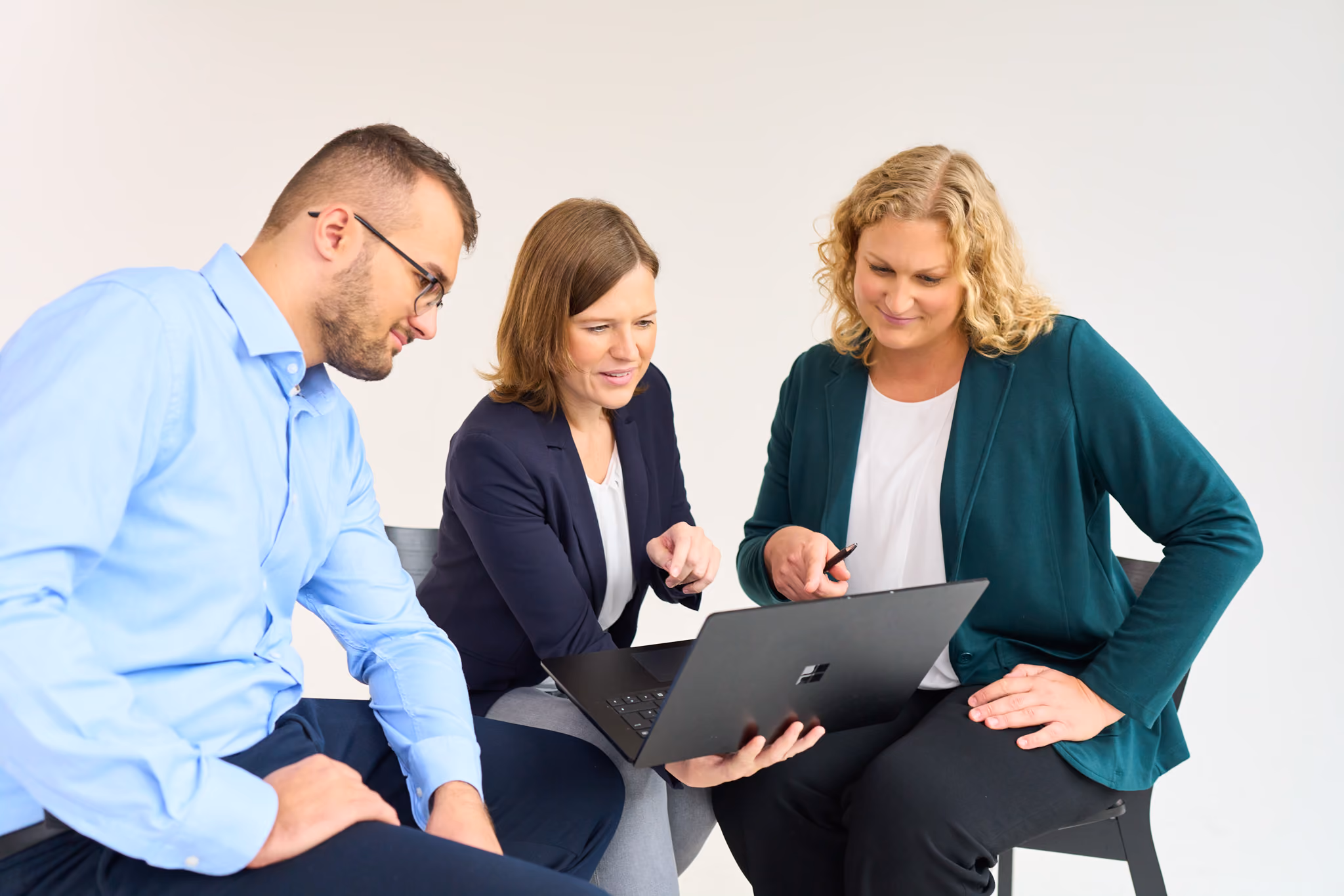Drei Kollegen von loyos bi schauen auf einen Laptop, zwei Frauen erklären dem Kollegen etwas.