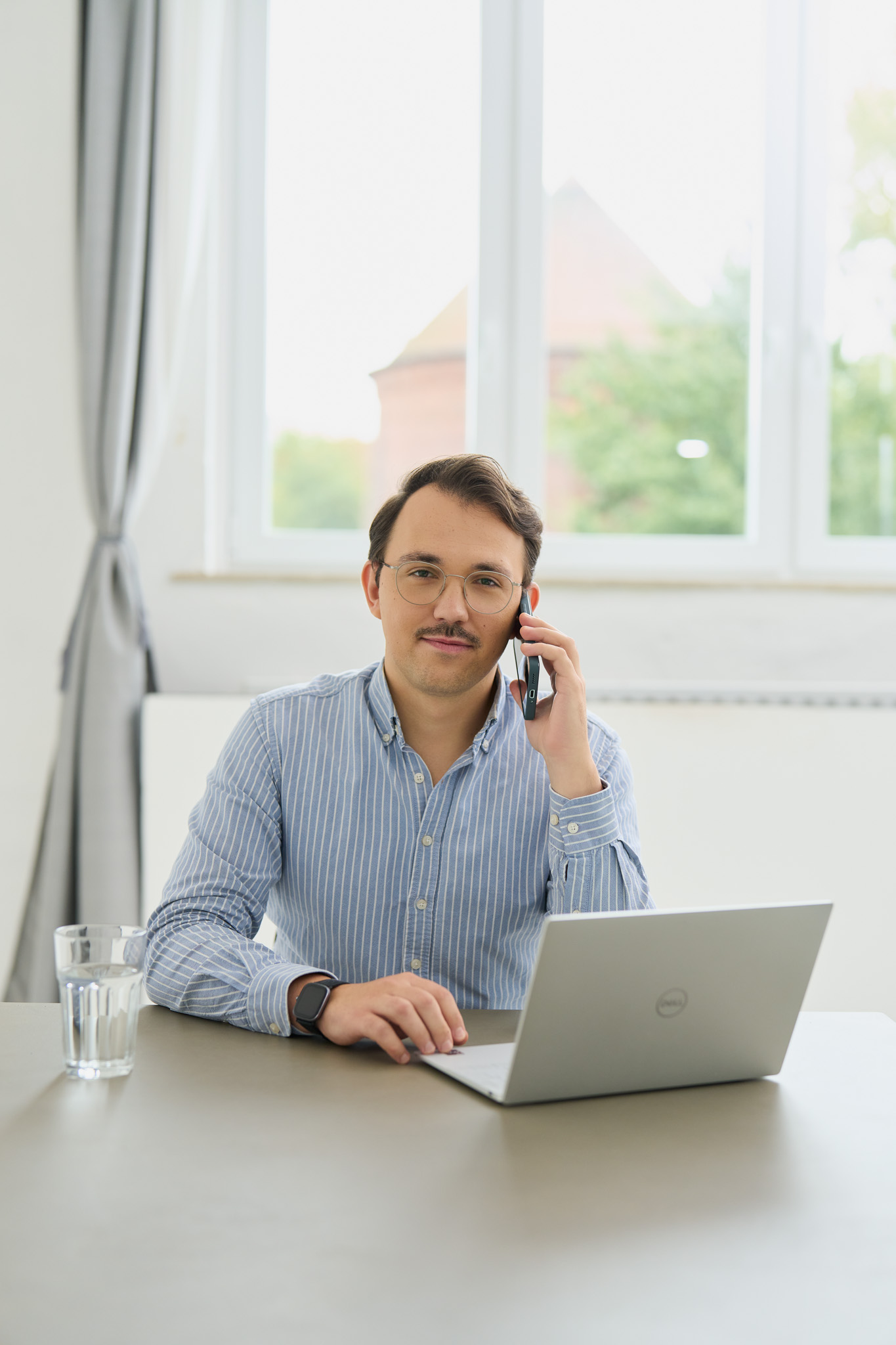 Florian von loyos sitzt am Laptop und telefoniert mit dem Handy