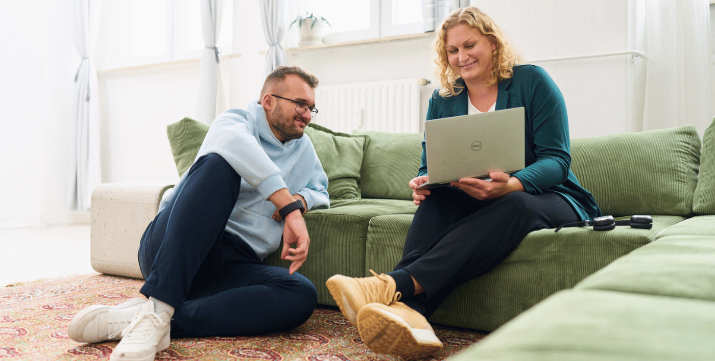 Zwei Kollegen von loyos sitzen und schauen auf einen Laptop.