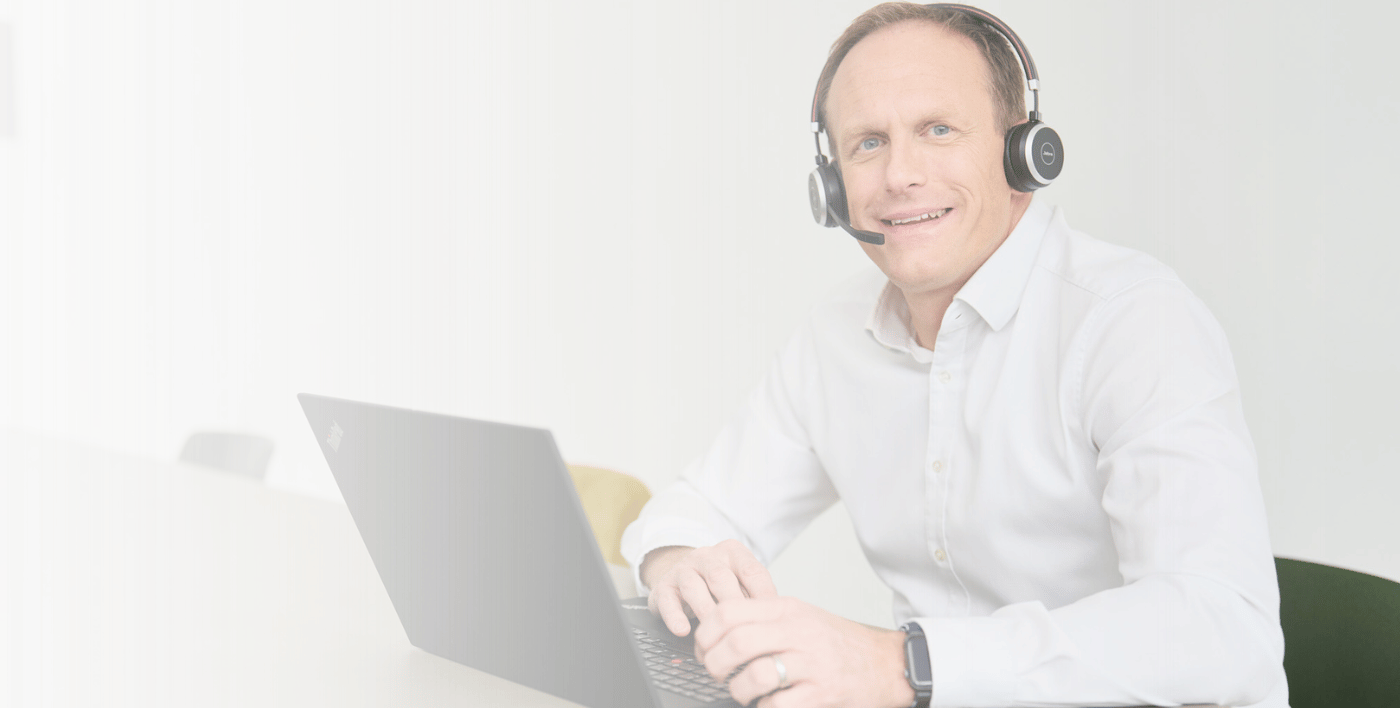 Ein Mann am Laptop mit Headset arbeitet für loyos bi im Service.