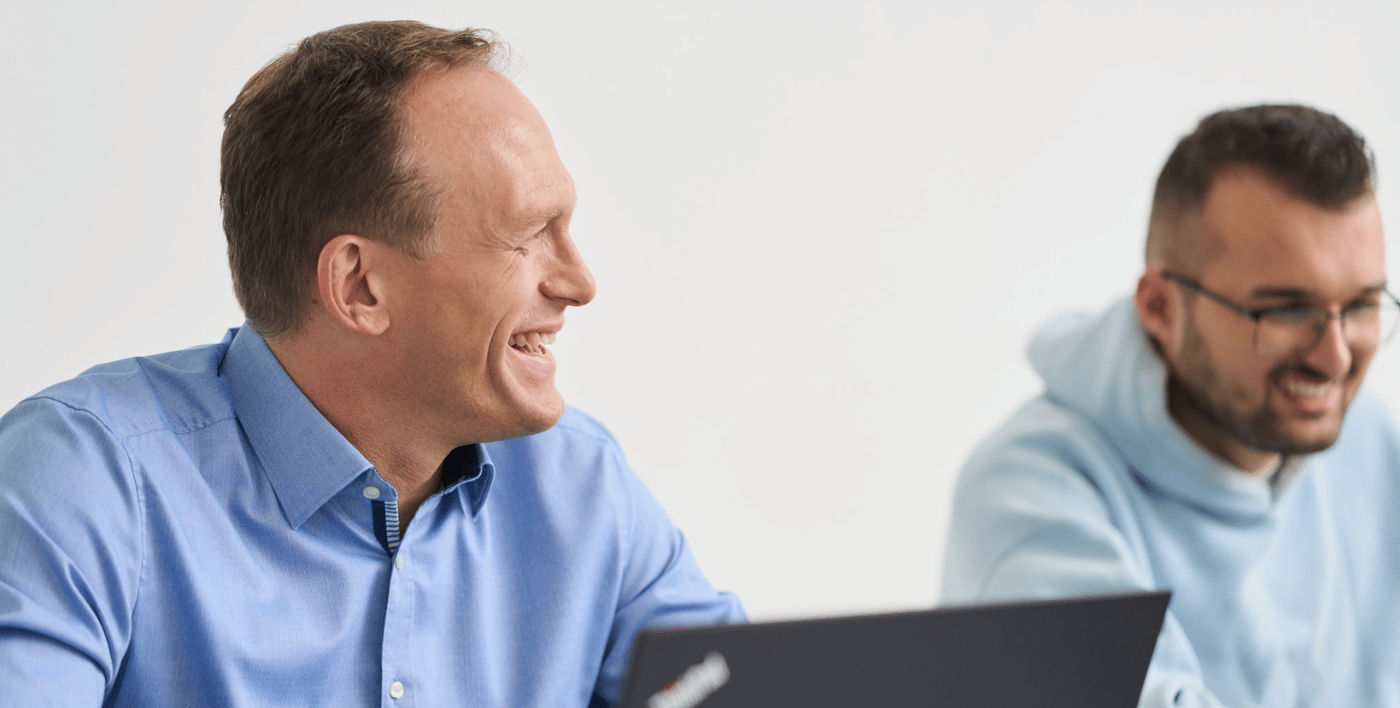 Ein Mann schaut zur Seite, lächelt seinen Kollegen von loyos bi an.