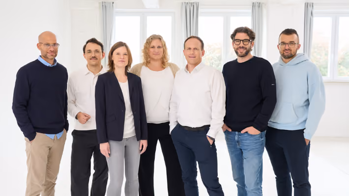 Das Team von loyos bi steht und lächelt in die Kamera. Es sind 7 Personen, davon zwei Frauen.