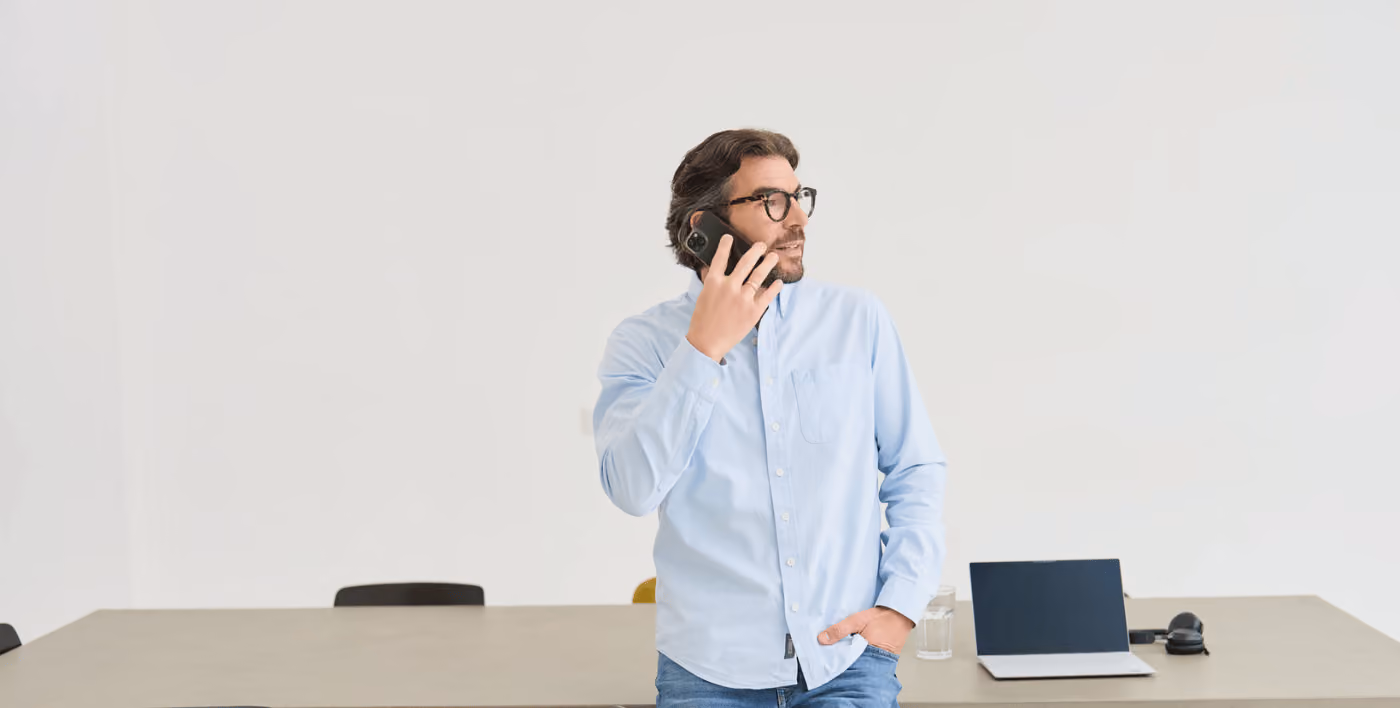 The founder and CEO of loyos bi, Martin Sperling, is leaning against a table, talking on the phone, looking to the side.