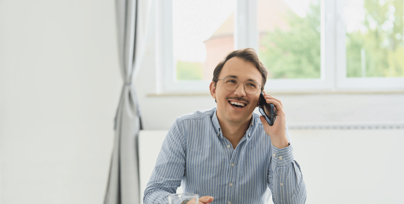 Florian von loyos bi lächelt nett, telefoniert dabei und sitzt am Tisch.