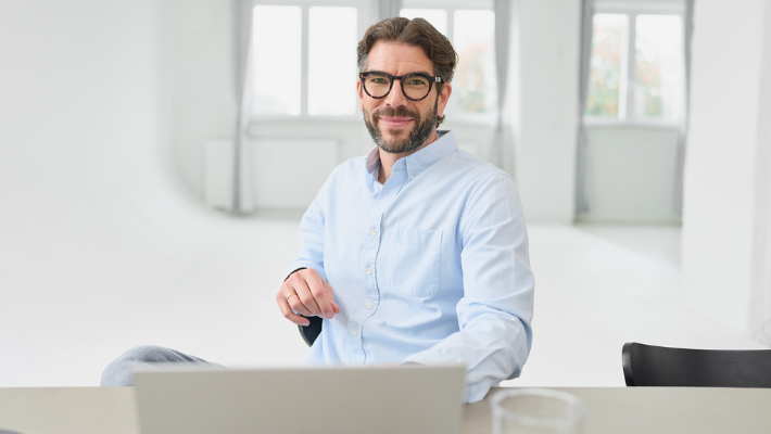 Der Gründer und Chef von loyos bi, Martin Sperling, sitzt am Schreibtisch, Laptop vor sich, er schaut in die Kamera.