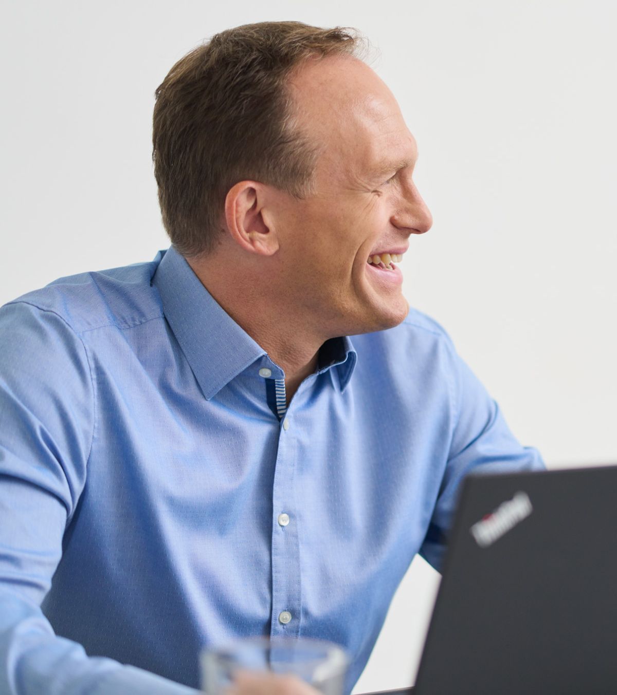 Ein Kollege von loyos bi lächelt, schaut zur Seite, er hat ein blaues Hemd an.