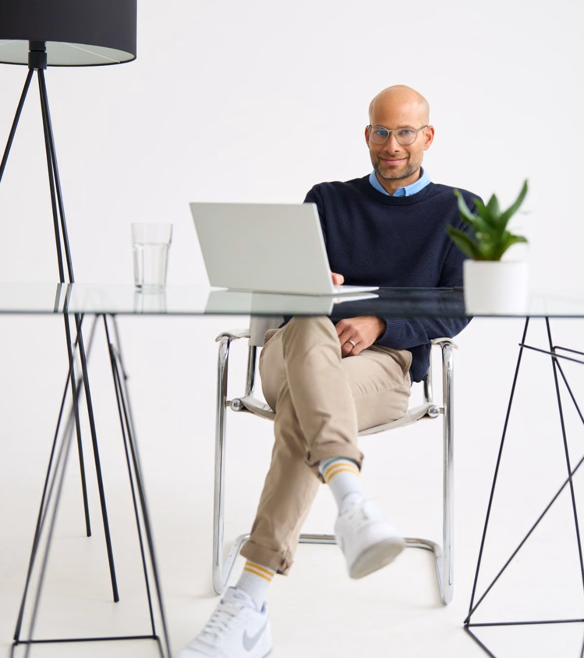 Ein Mann wird von unten fotografiert, er sitzt an einem Glastisch, sein Laptop vor sich. Er arbeitet bei loyos bi.