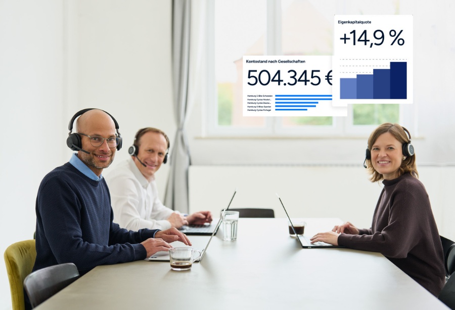 Zwei Männer und eine Frau von loyos bi sitzen am Tisch, ihre Laptops vor sich.