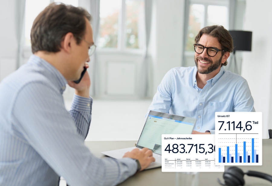 Florian und Martin sitzen am Tisch, lachen, man sieht Zahlen zur GuV.