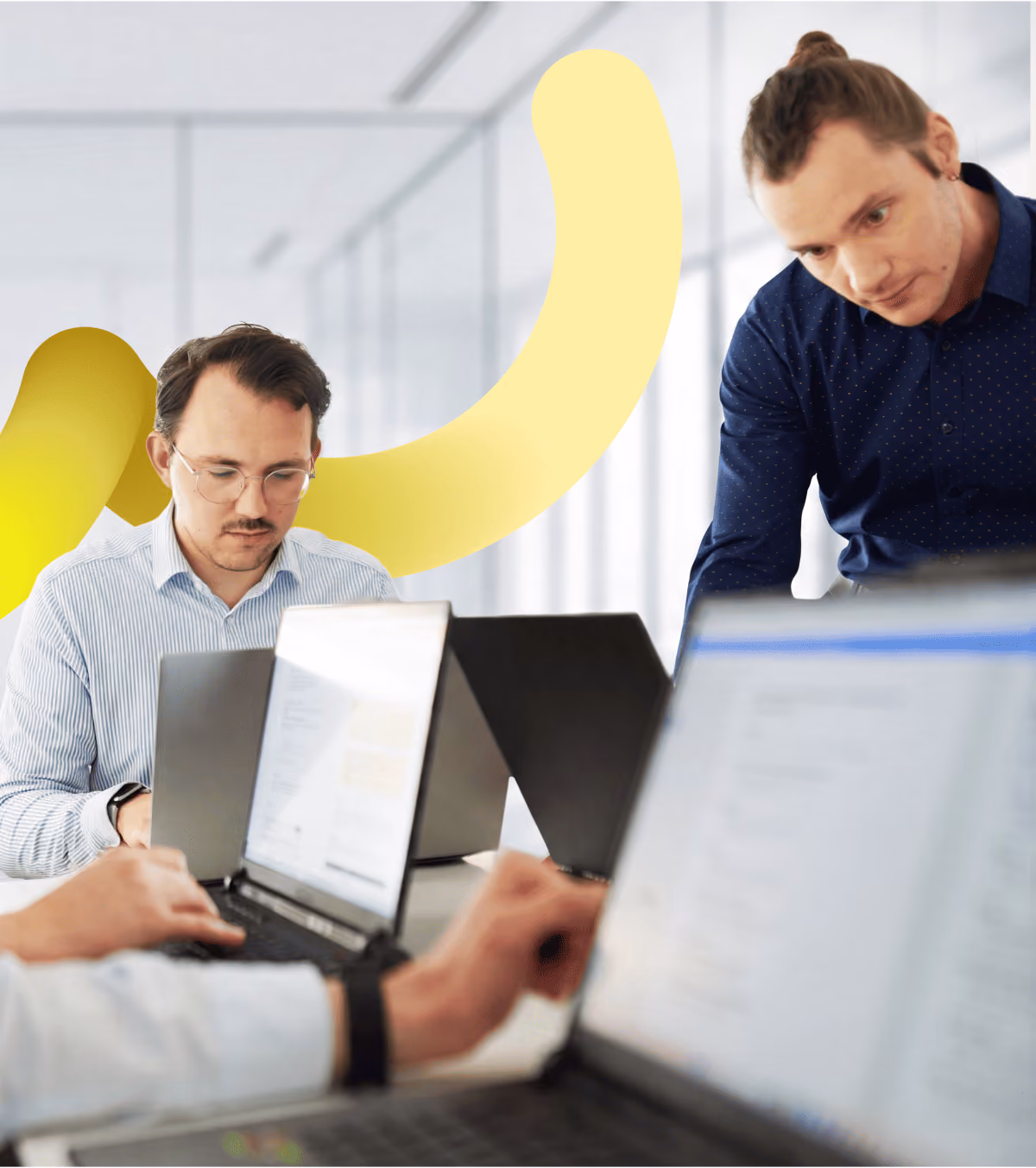 Zwei junge Männer von loyos arbeiten konzentriert an ihren Laptops.