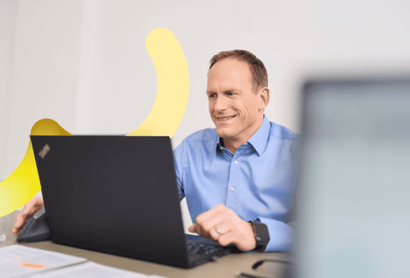 Ein Mitarbeitender von loyos sitzt am Laptop und bearbeitet vermutlich Kundenanfragen. Er sieht zufrieden aus.