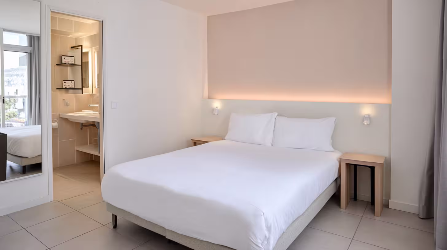 Chambre double lumineuse de l’Hôtel des Arceaux, lit queen-size avec tête de lit rétroéclairée et salle de bain attenante.