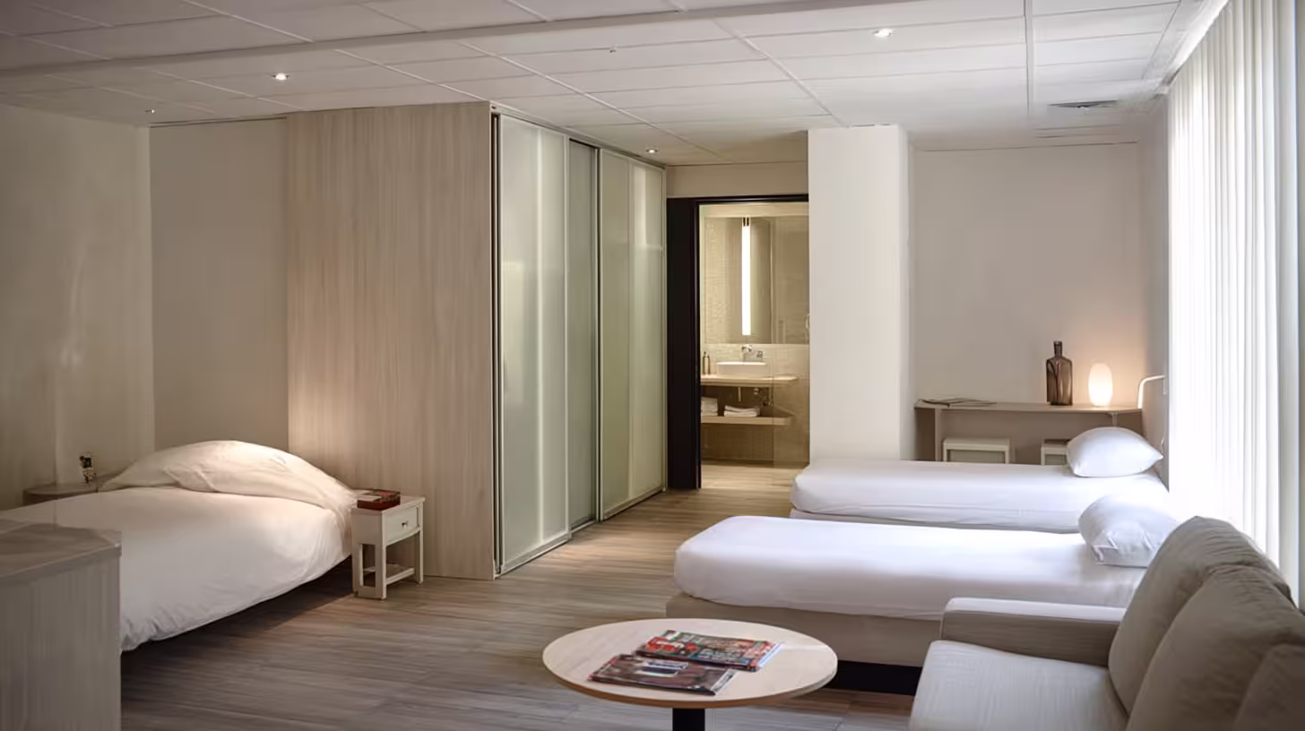 Chambre familiale spacieuse de l’Hôtel des Arceaux, quatre lits, coin salon et salle de bain moderne.