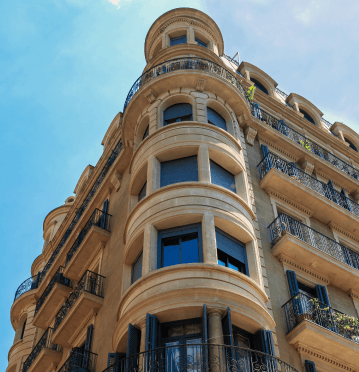 Elegant apartment building showcasing historic architecture, including a rounded corner, balconies, and detailed stonework.