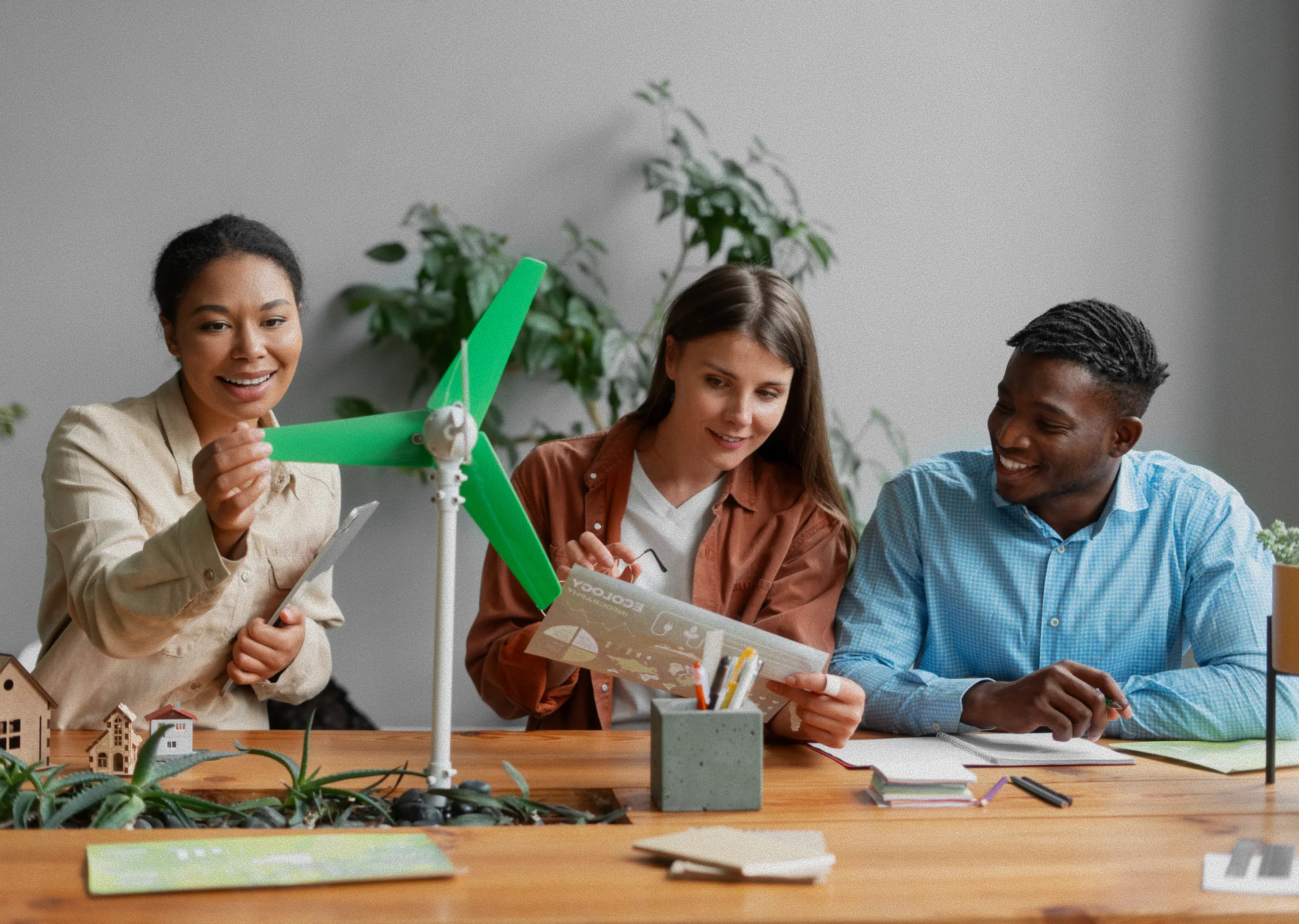 Three classmates working closely together, reading from a shared study guide.