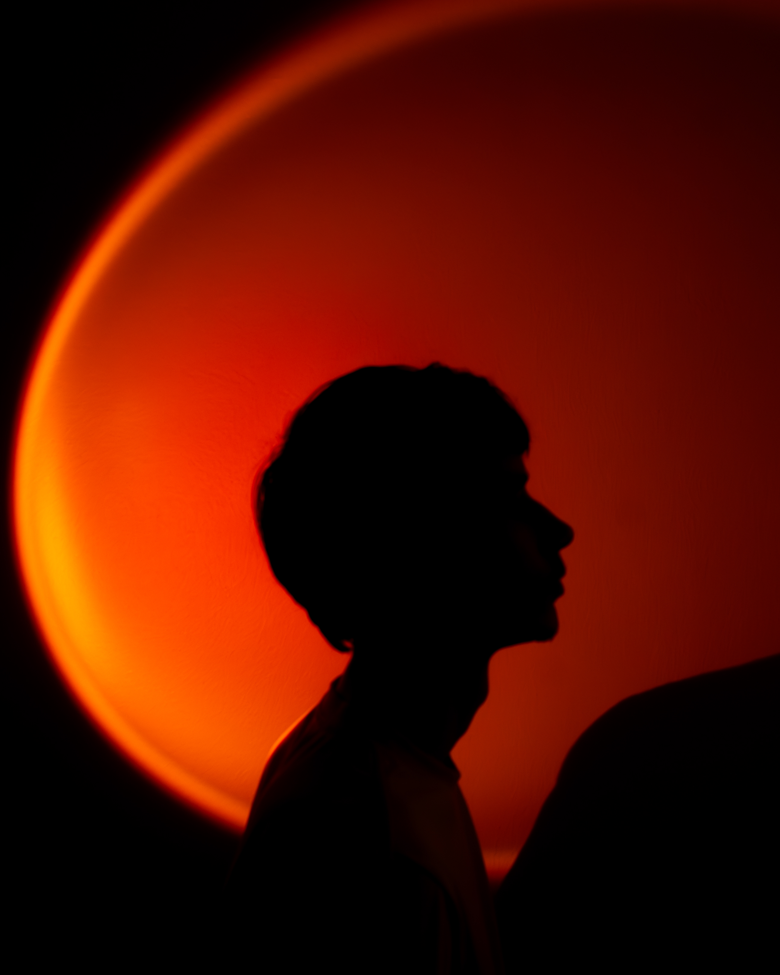 Silhouette of a person's profile against a glowing red-orange circular background.