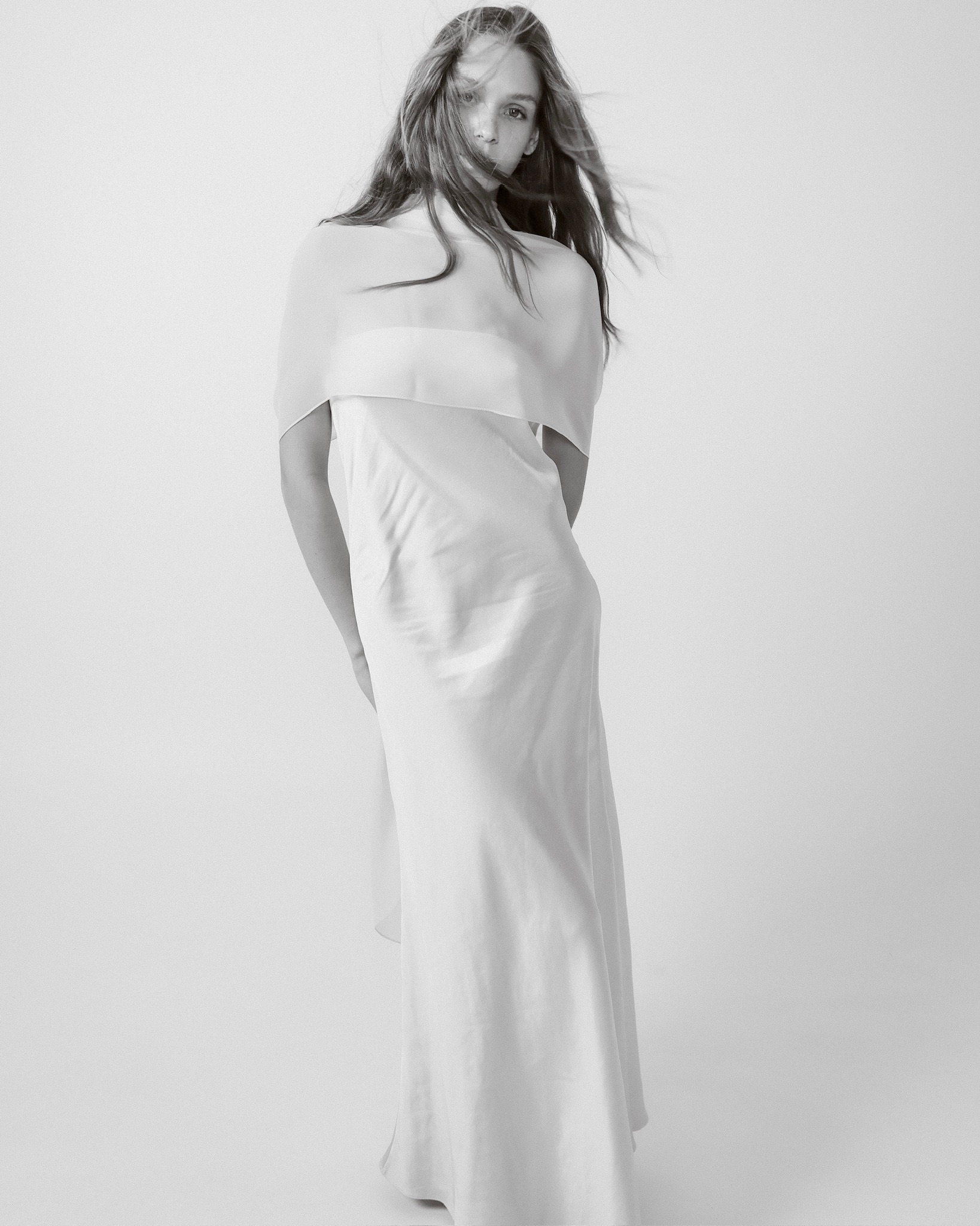 Женщина в воздушном белом платье с полупрозрачной накидкой — коллекция 9ATELIER
