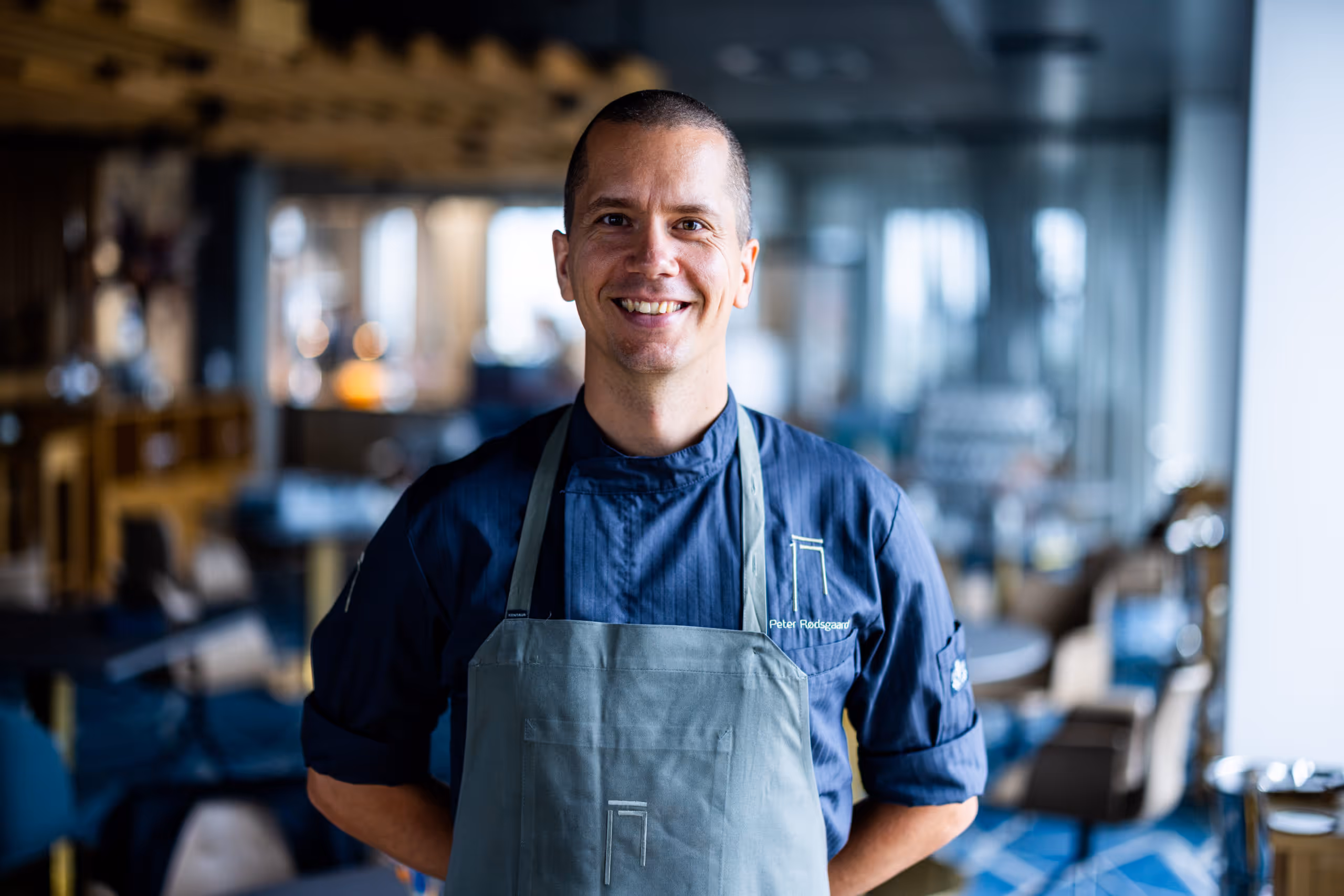 Peter Rødsgaard i kokkeuniform og forklæde stående i en resturant syttende restaurant.
