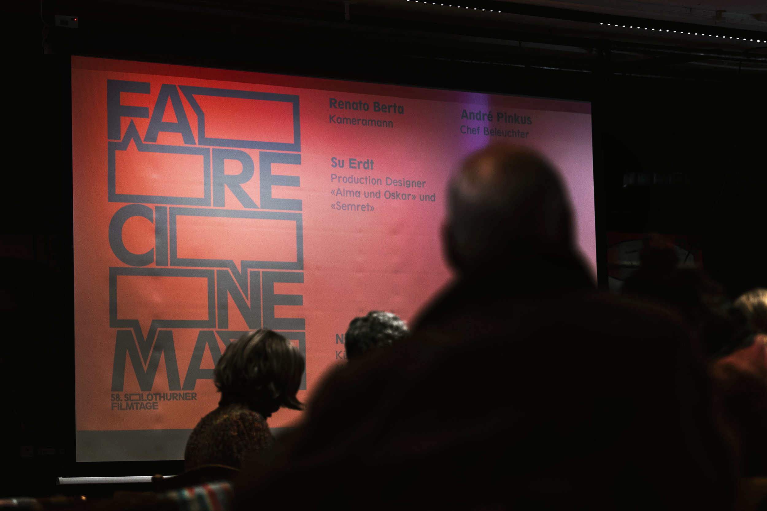The red "Fare Cinema" visual with black typography on a big screen with people in front of it