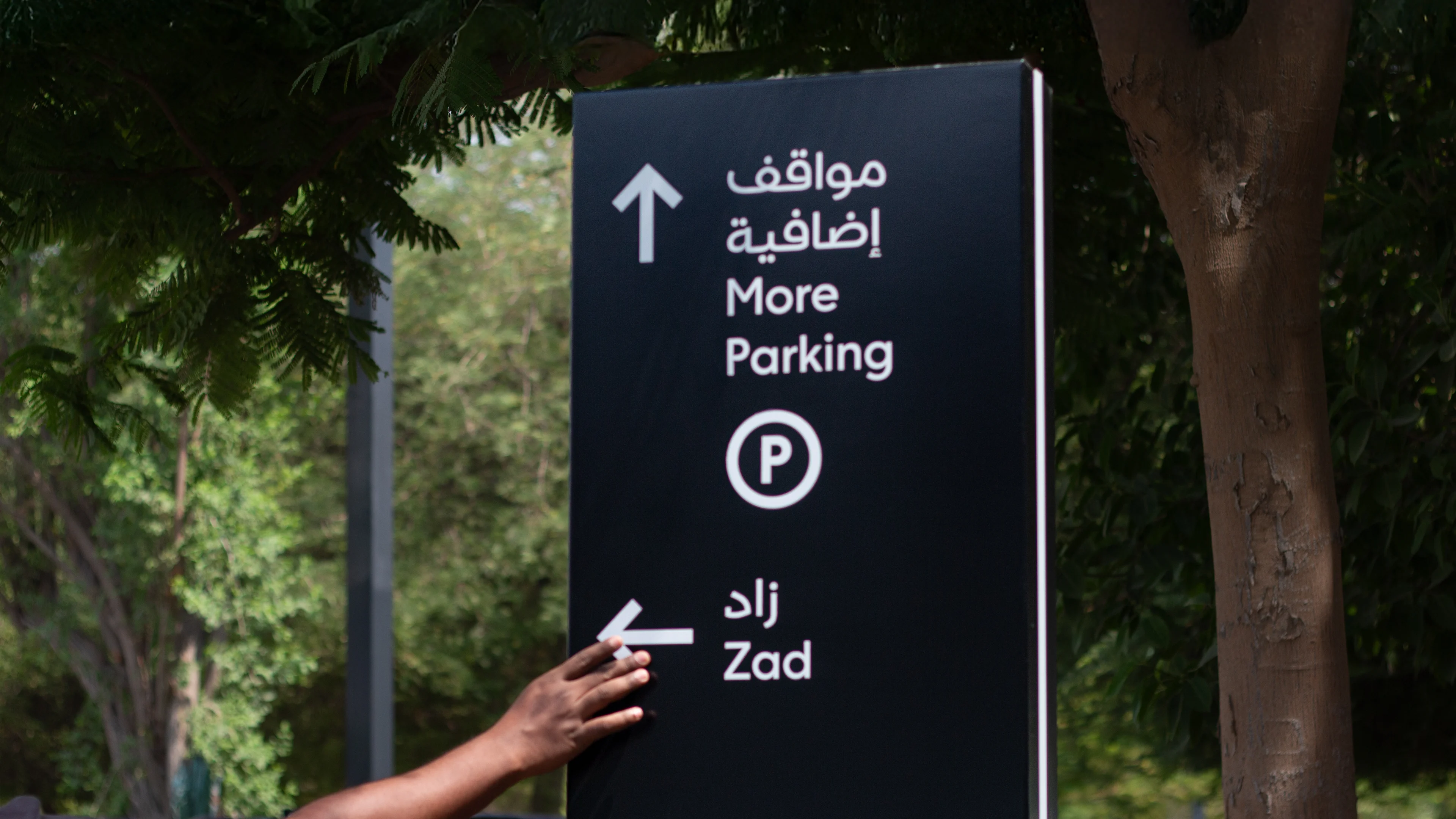 LIMAH designer reviewing pedestrian wayfinding signage on site, demonstrating technical delivery and design governance in Aljada