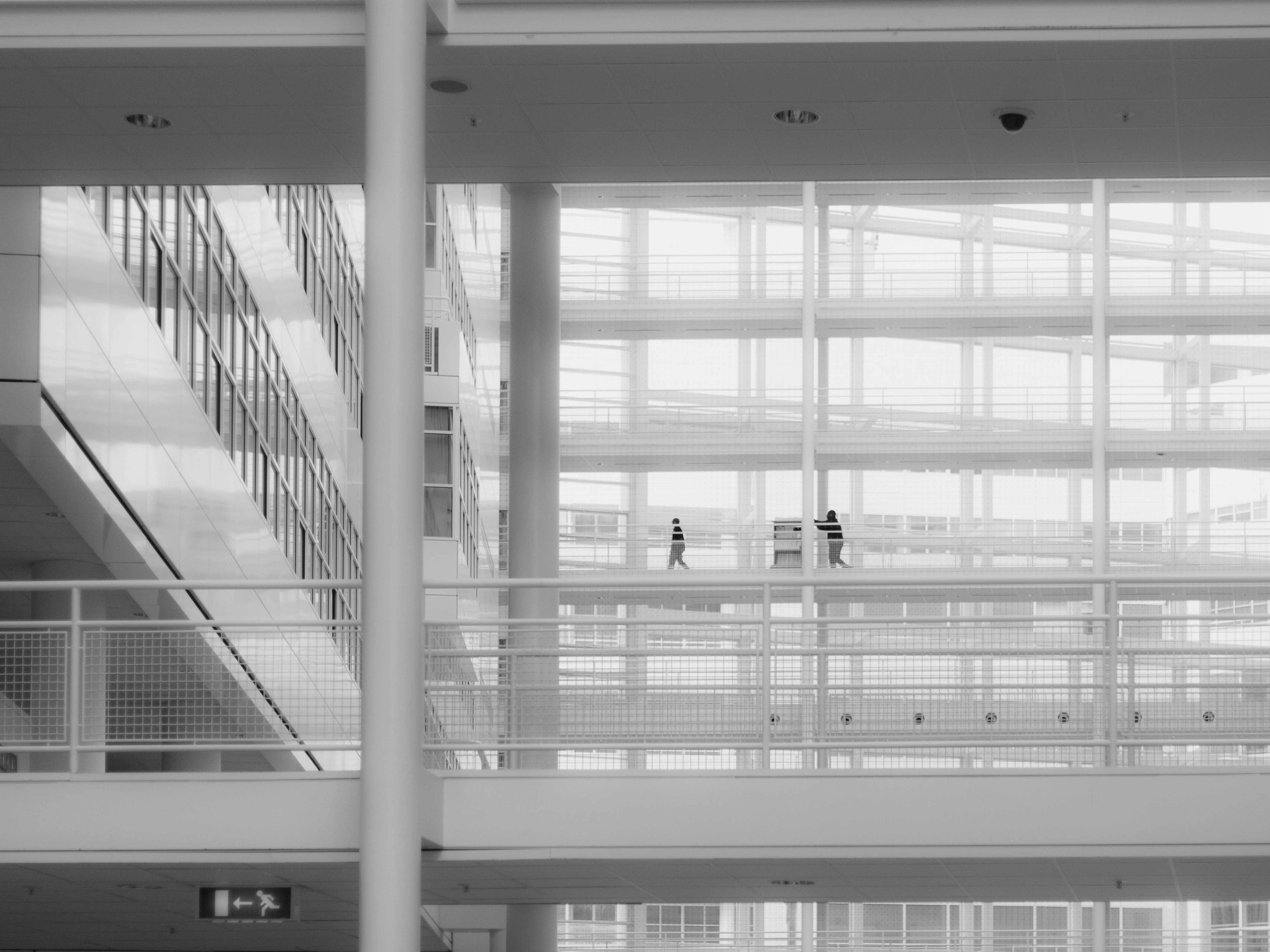 Black and white image of modern architecture with people walking on elevated paths.