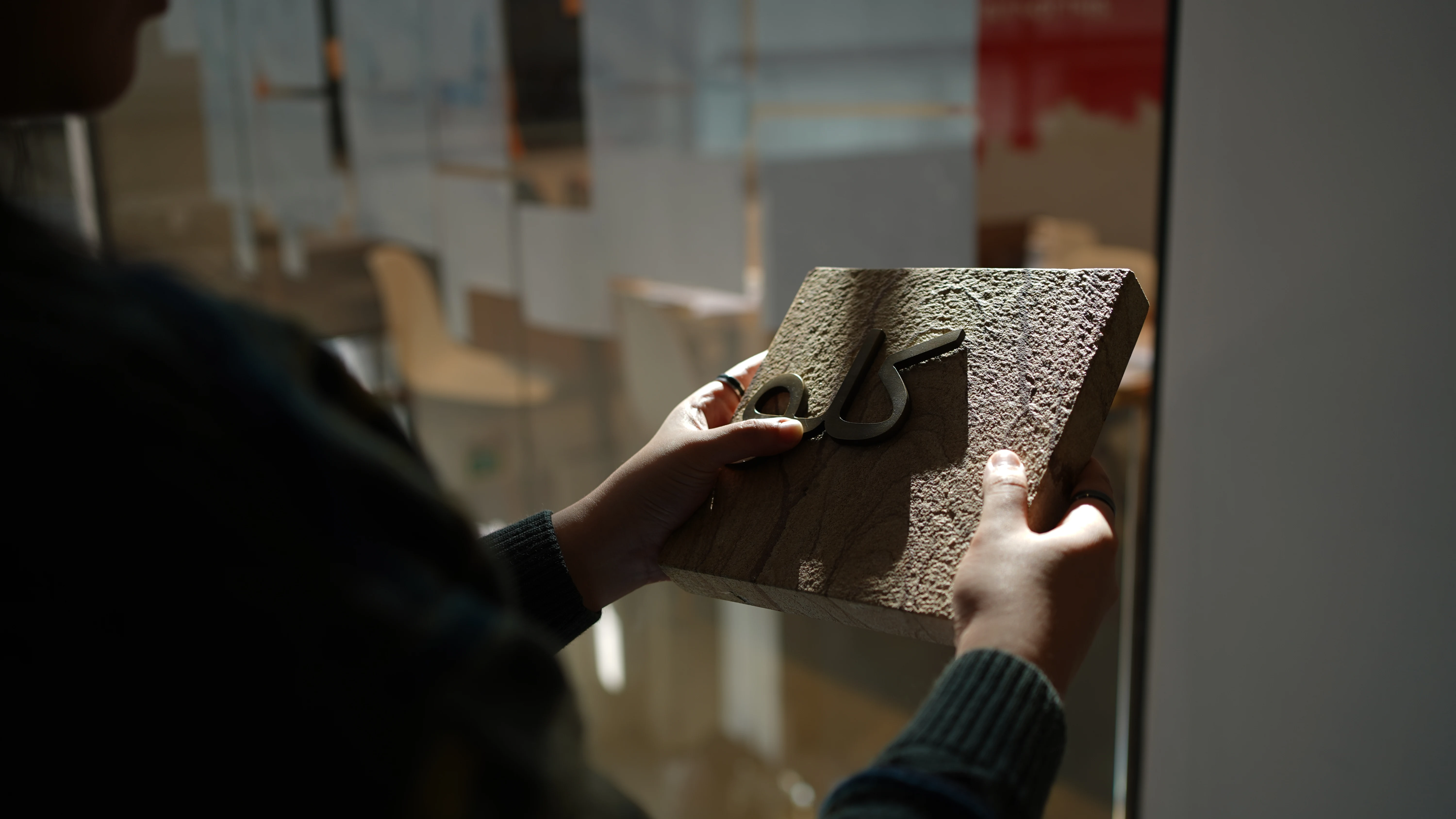 LIMAH designer testing Arabic lettering materials against textured stone for a tactile experience