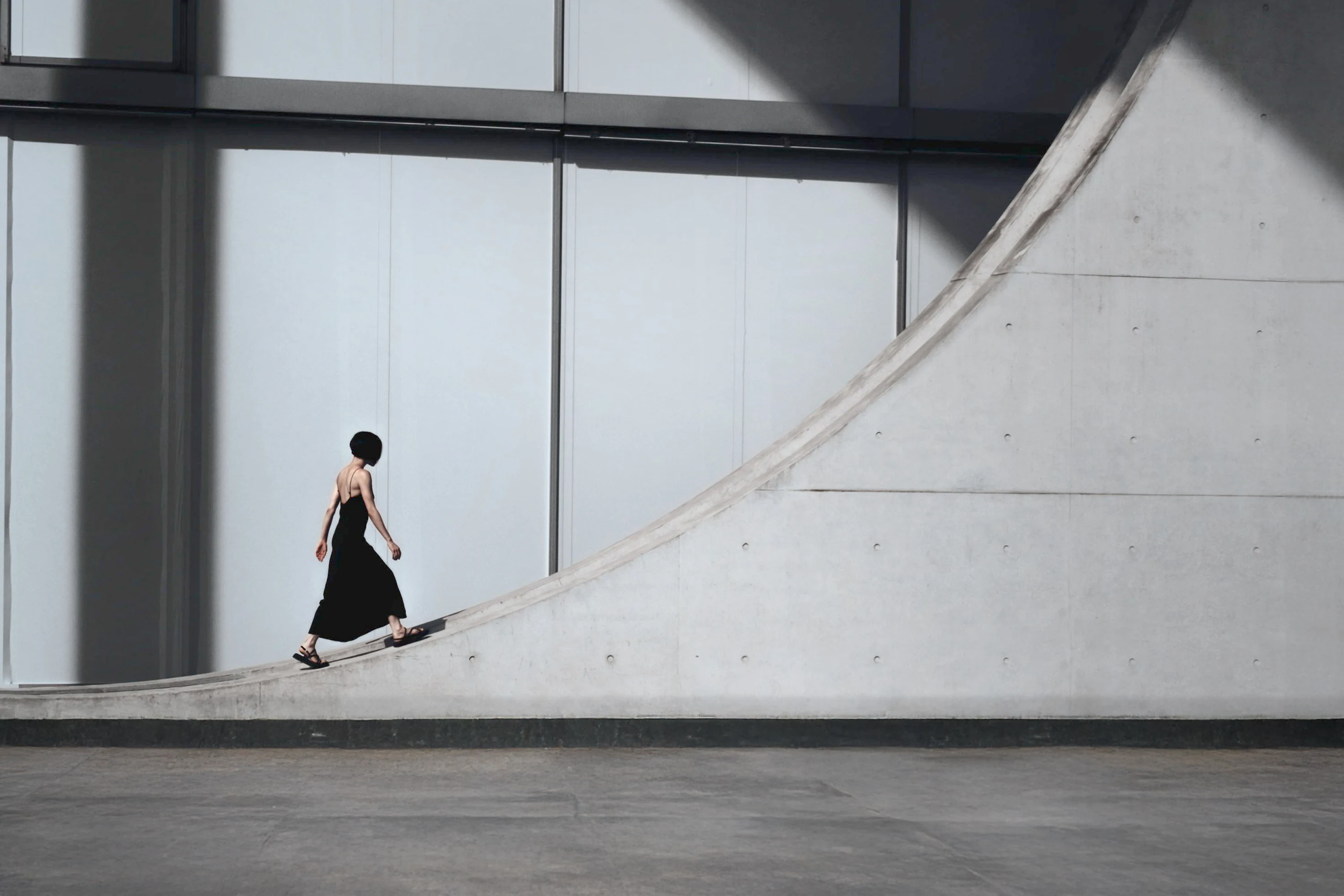 A woman walking near the iconic geometry of Berlin's modern architecture, creating a dramatic silhouette in sunlight and shadow.