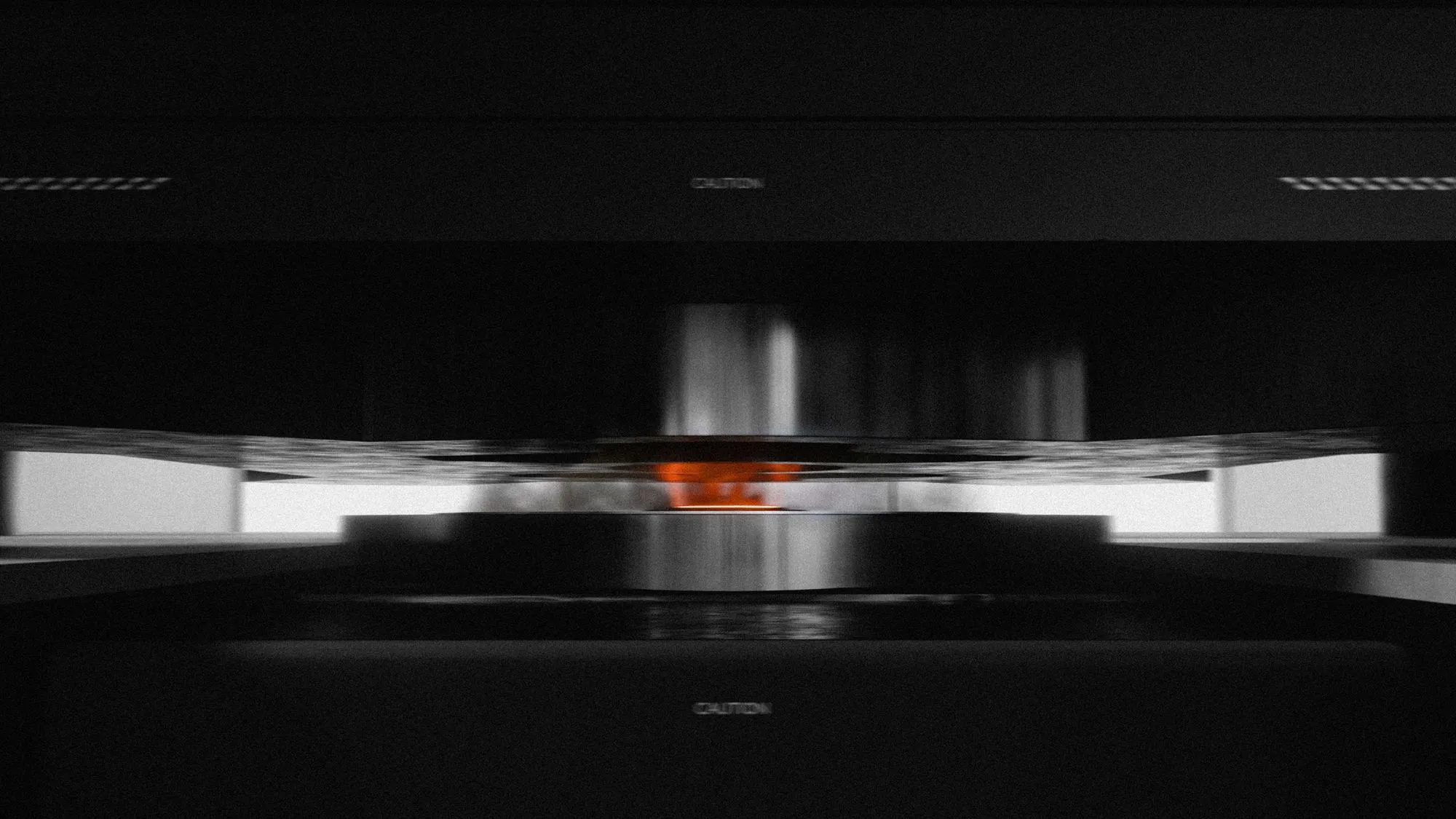 Close-up of a 3D printer nozzle extruding molten material in a dark environment with caution labels visible.