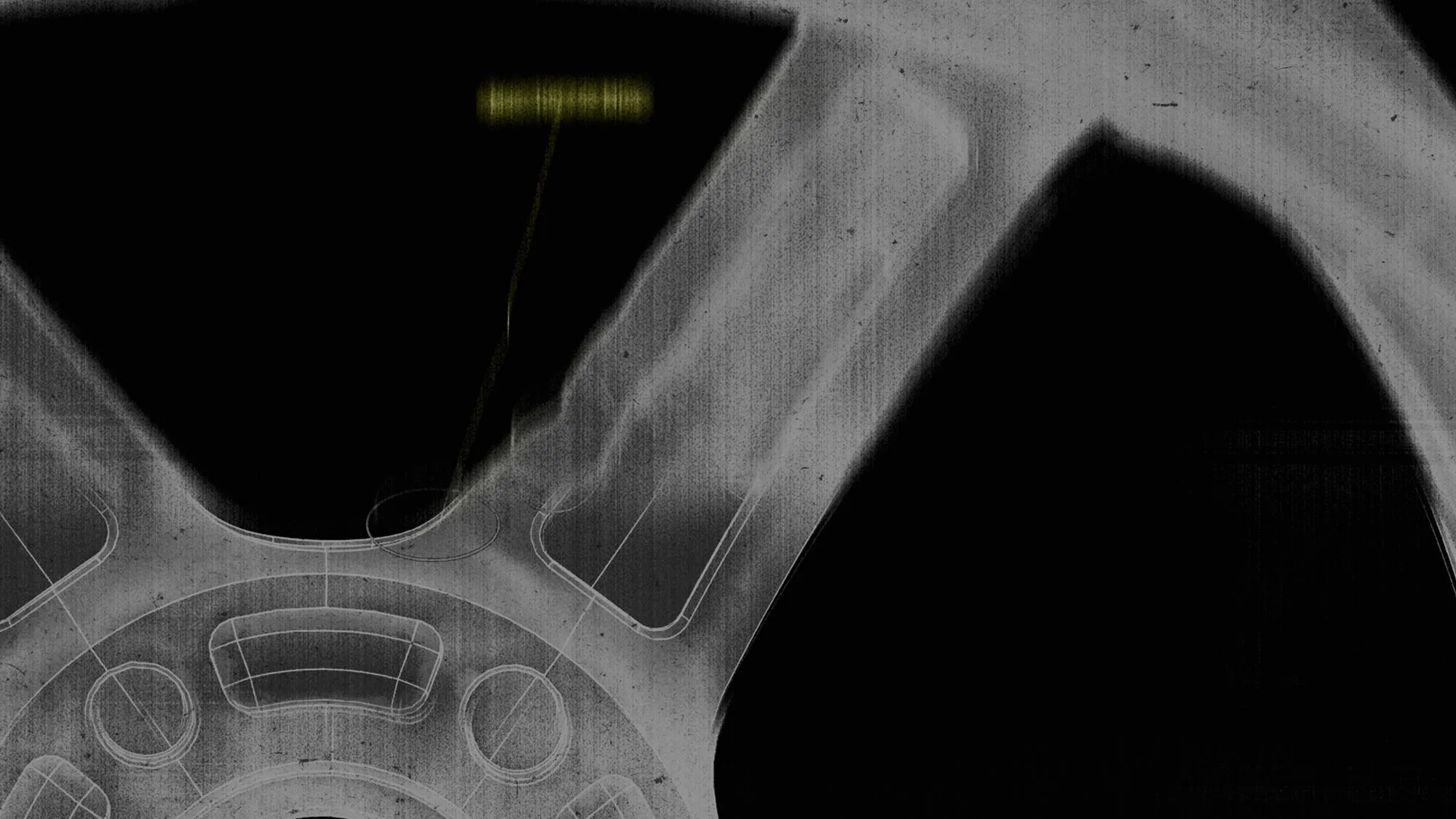 Grainy black and white close-up of a mechanical gear with a blurred yellow label.