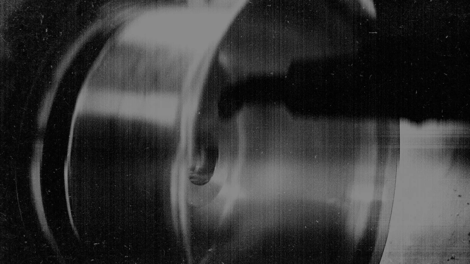 Close-up black and white image of a metal object with a curved surface and a circular feature.