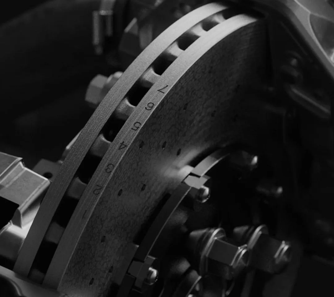 Close-up of a ventilated brake disc and caliper assembly in black and white.